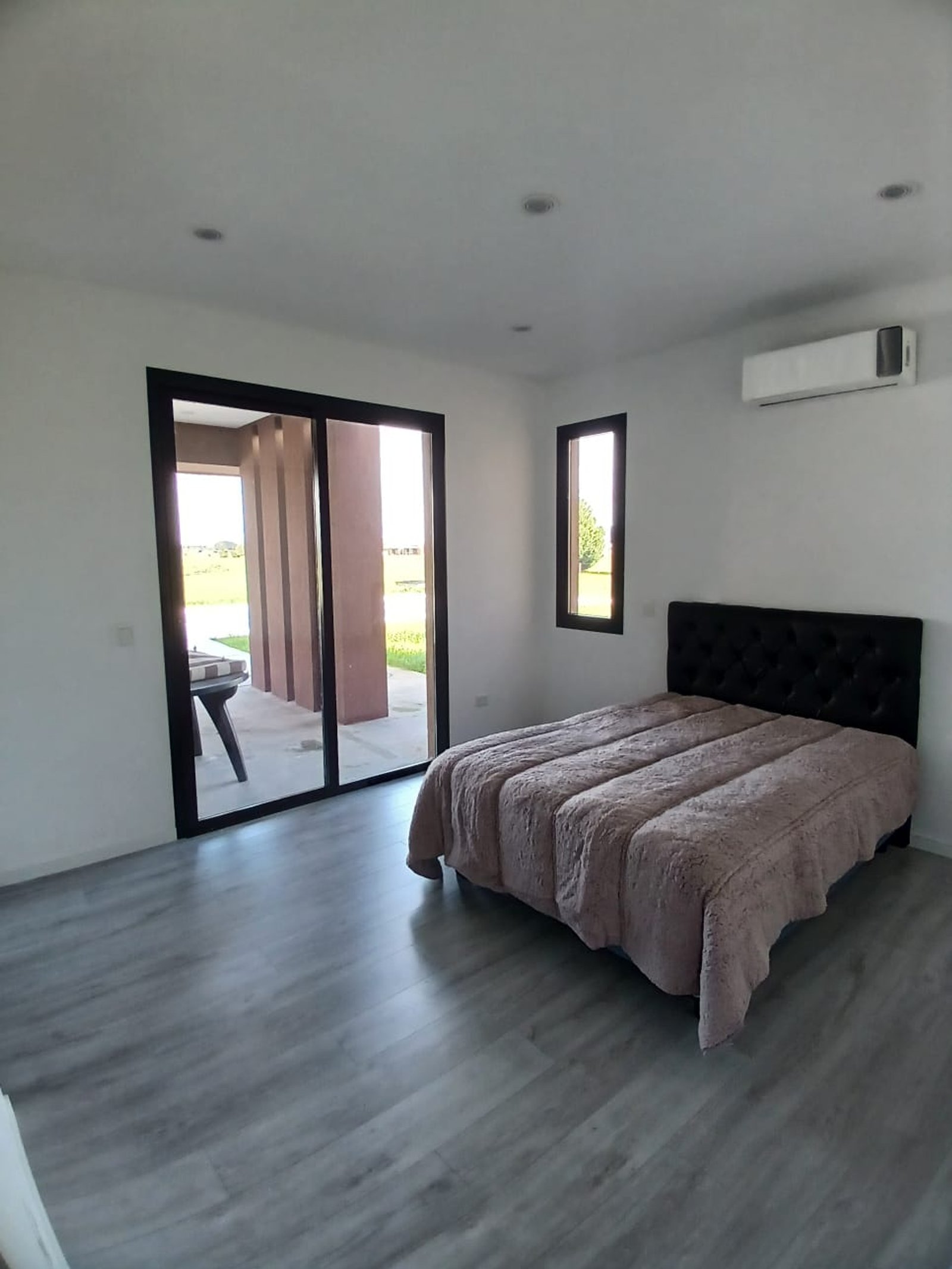 Dormitorio moderno con piso de madera gris y puertas corredizas — proyecto CASA A Y M, por Sep Arquitectura , en Ruta 205 Km 53